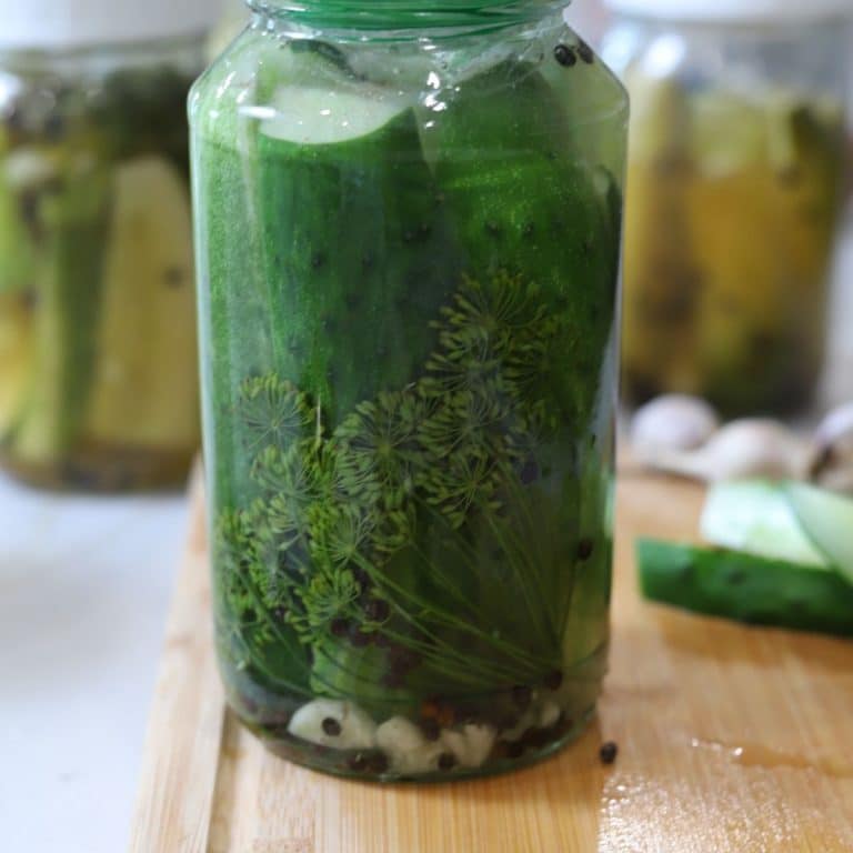 Half sour pickle recipe, finished half sour pickles on cutting board with a jar of fresh half sour pickles.